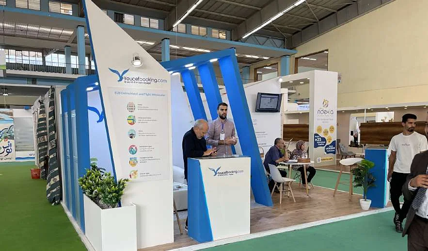 Stand Youcefbooking.com : voiles bleues inclinées, comptoir et espace de rendez-vous